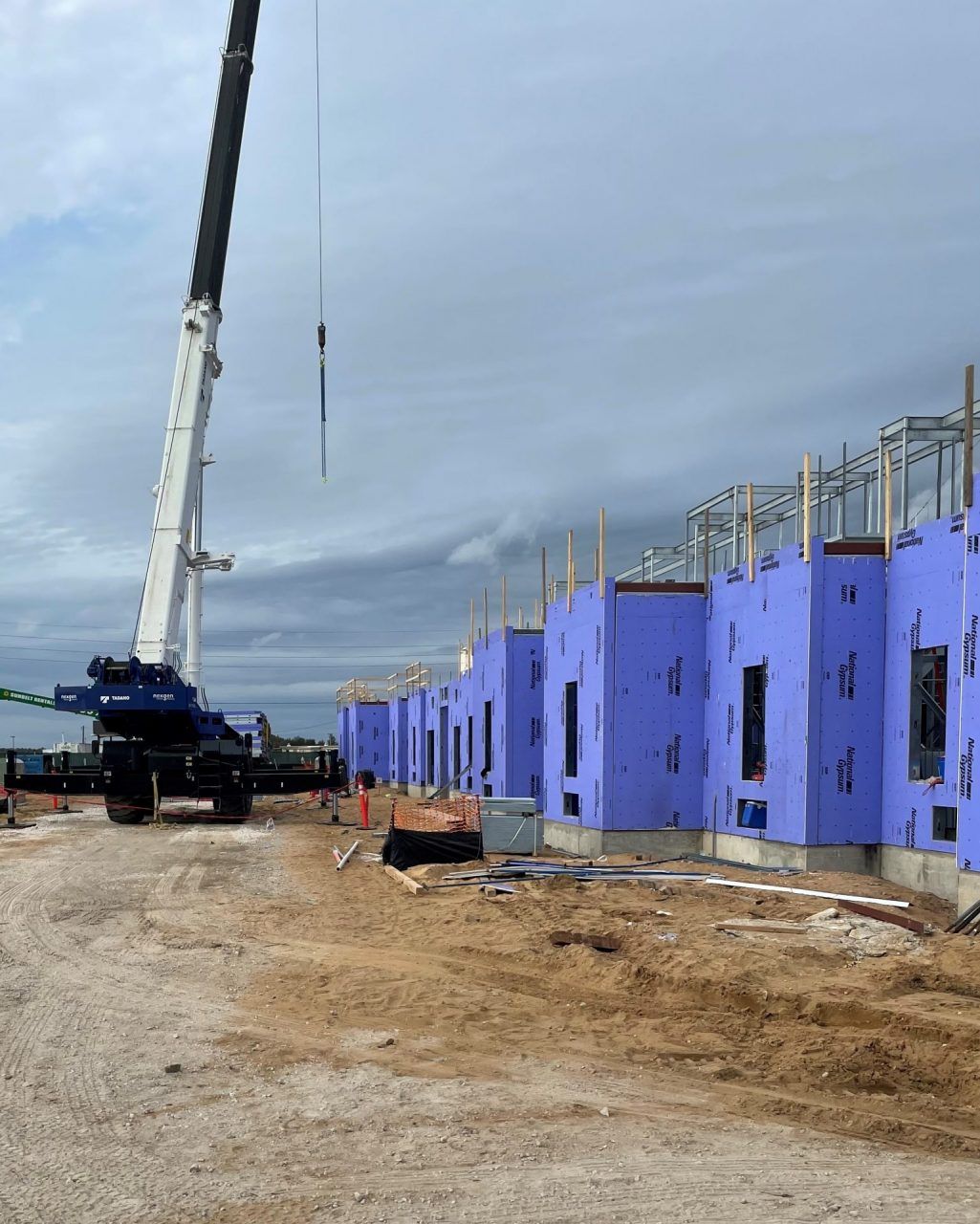 A construction site with blue buildings and a crane.