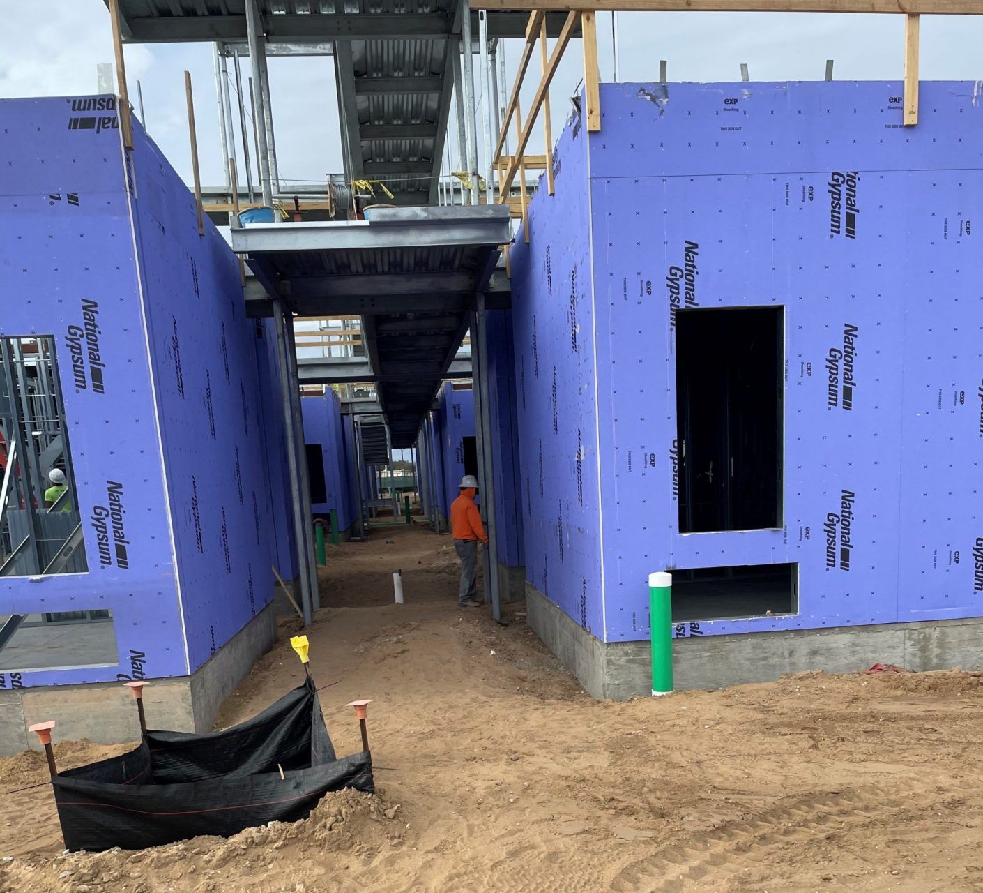 A man standing beside of a building under construction.
