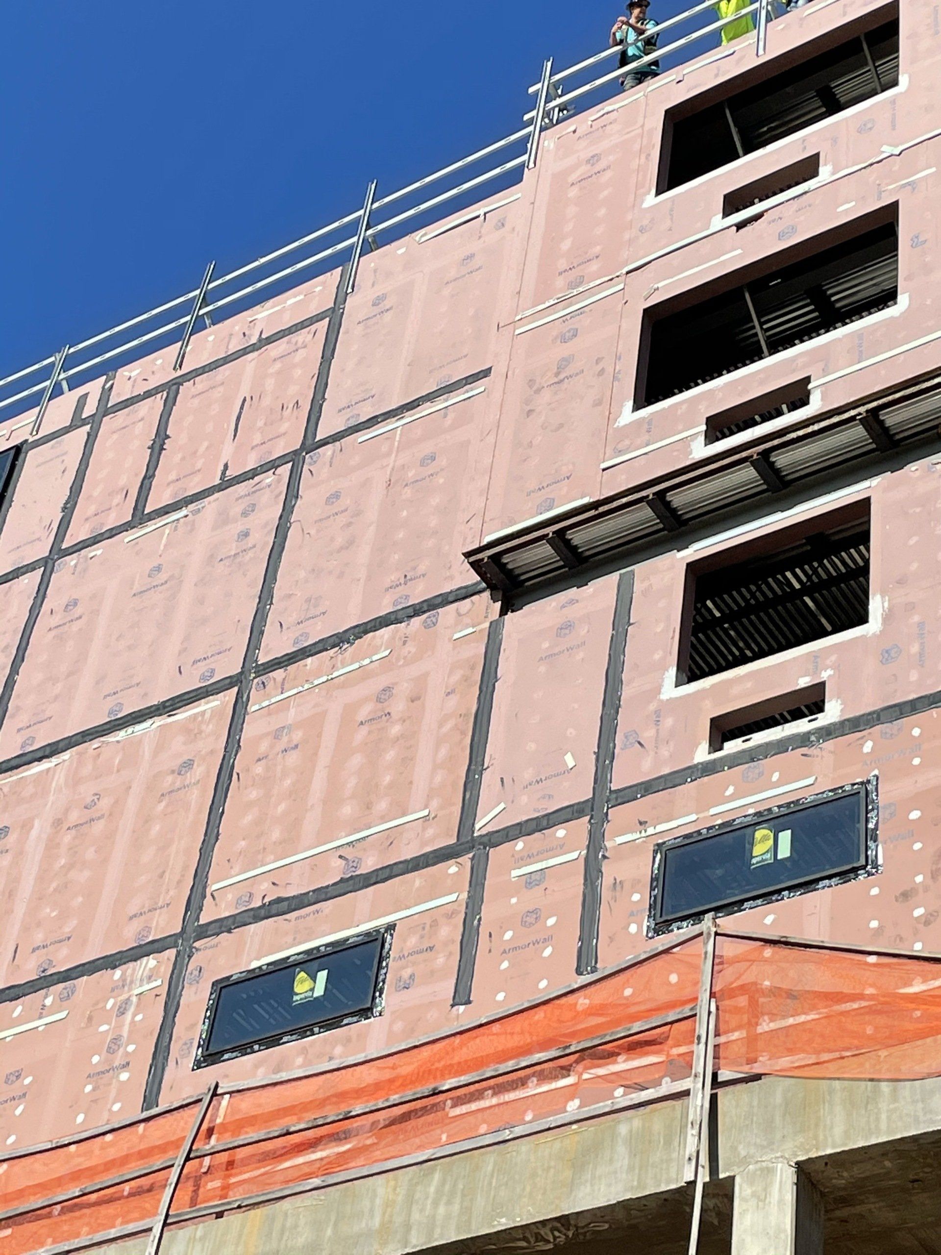 A large building is being built with a blue sky in the background.