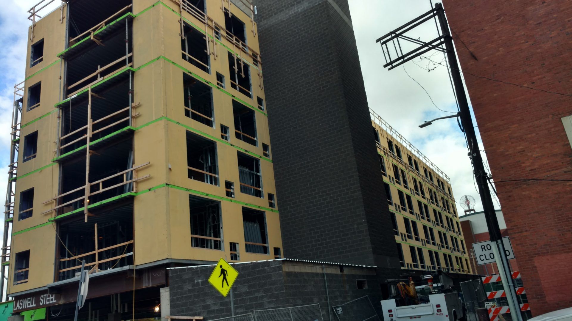 A building under construction with a yellow sign that says crosswalk.