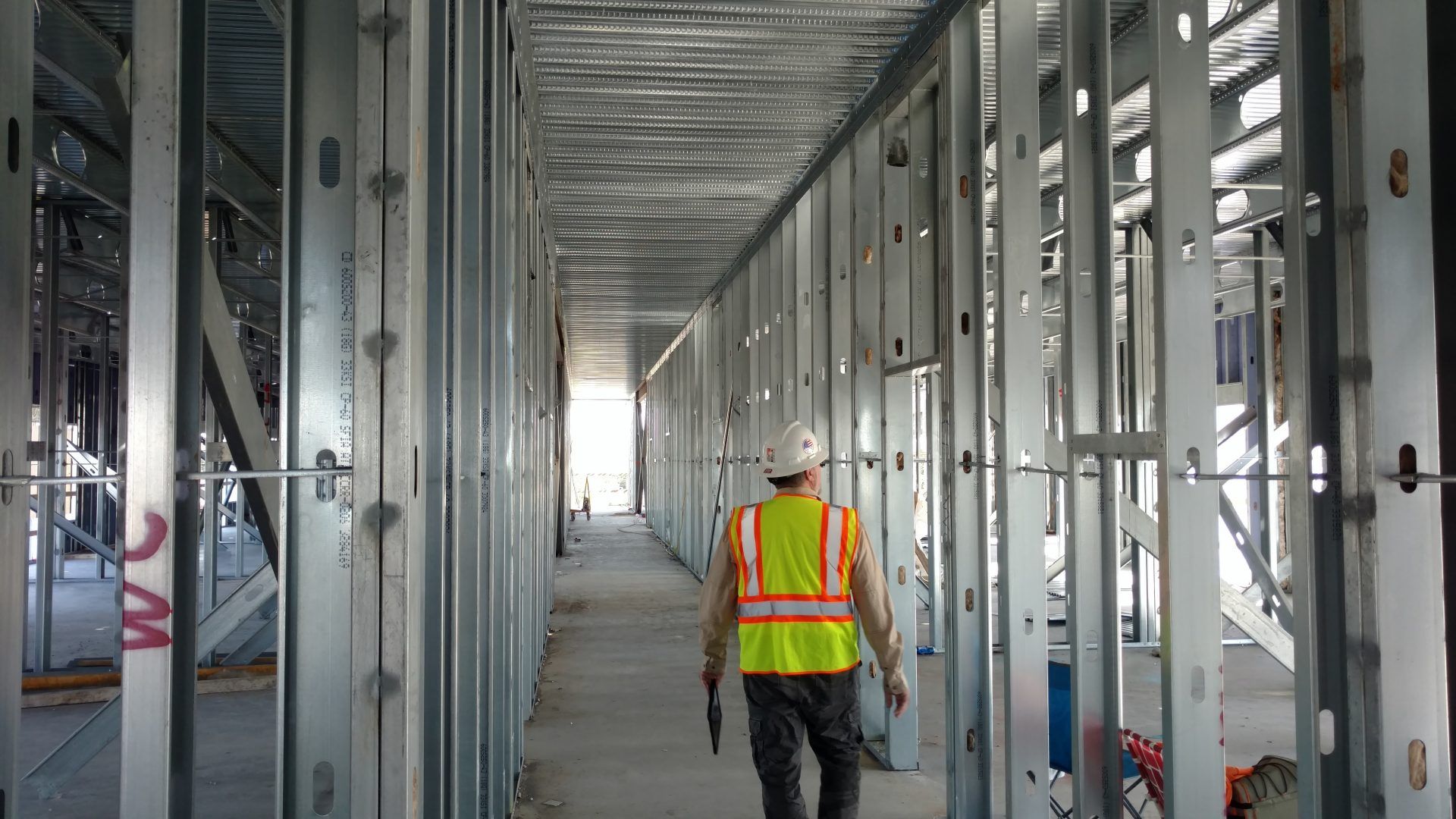 A construction worker is walking down a hallway in a building under construction.