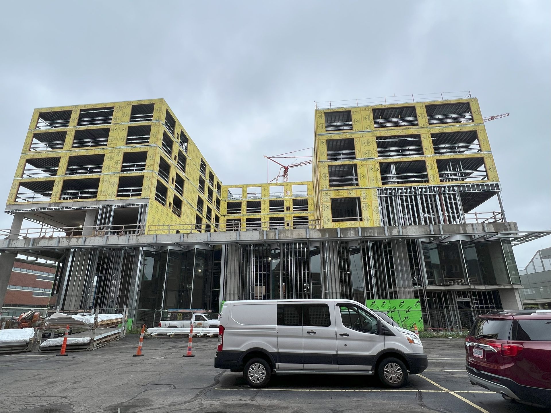 A white van is parked in front of a building under construction.