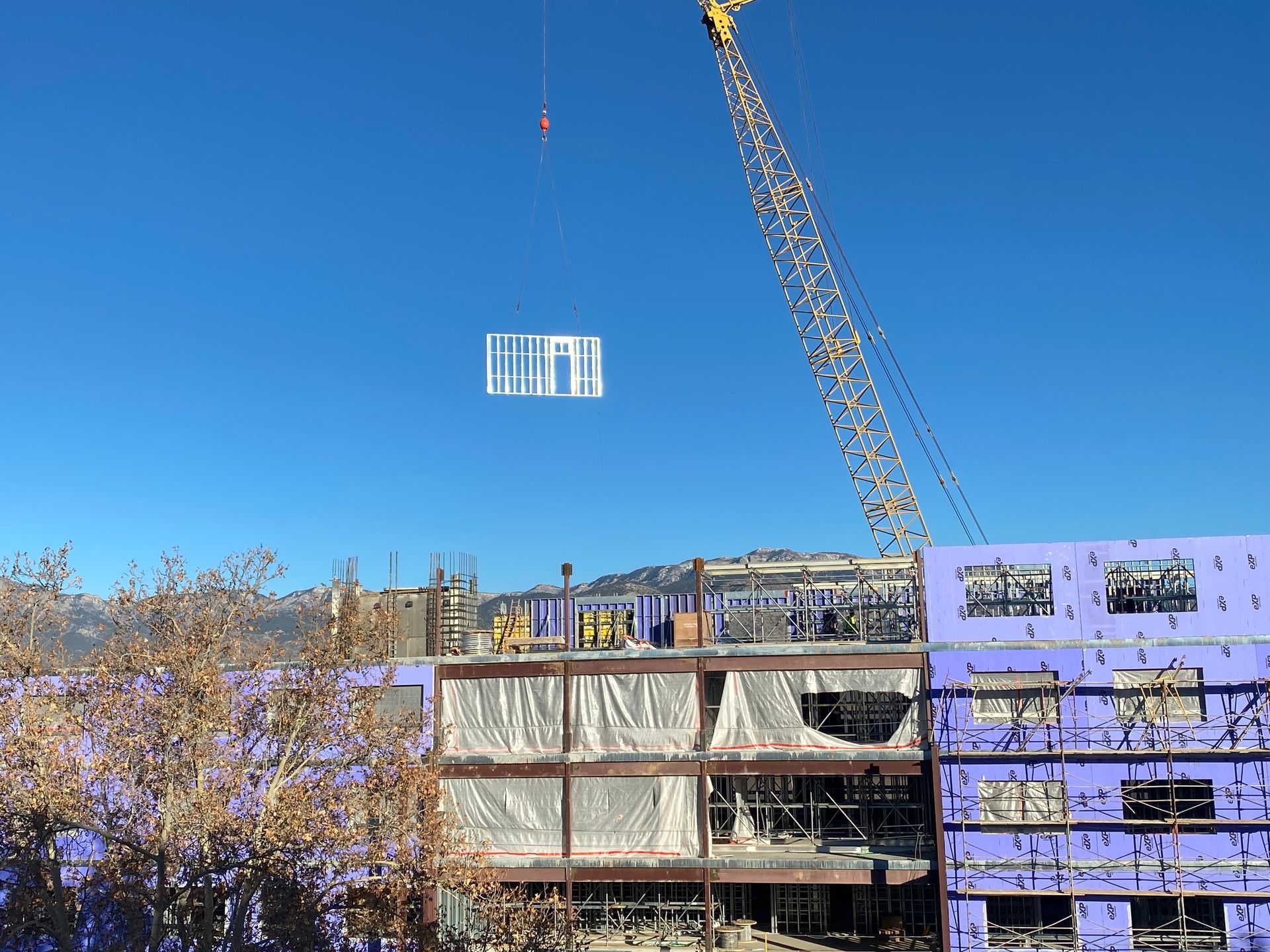 A large building under construction with a crane lifting a sign in the sky.