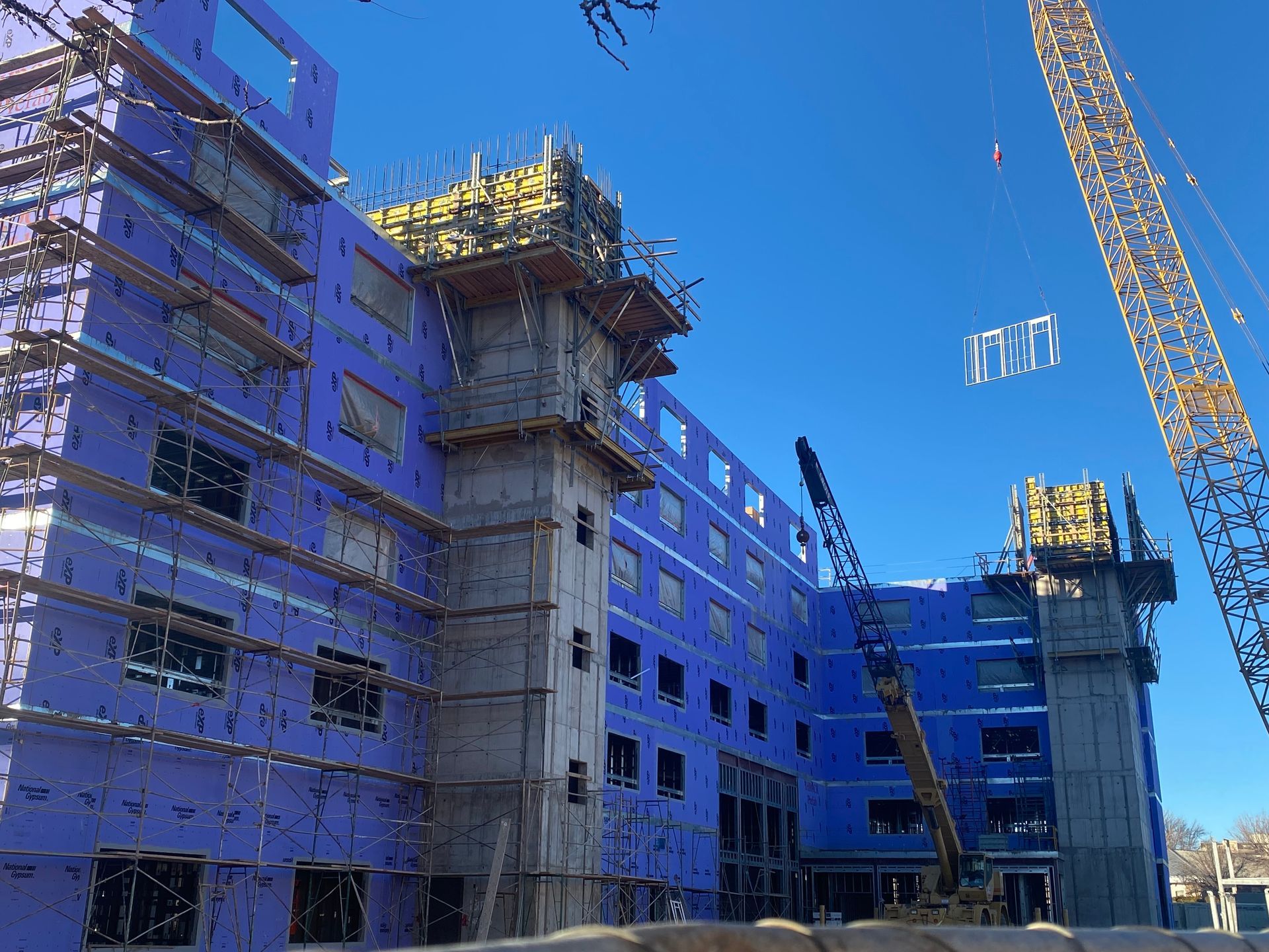 A large building under construction with a crane in front of it.