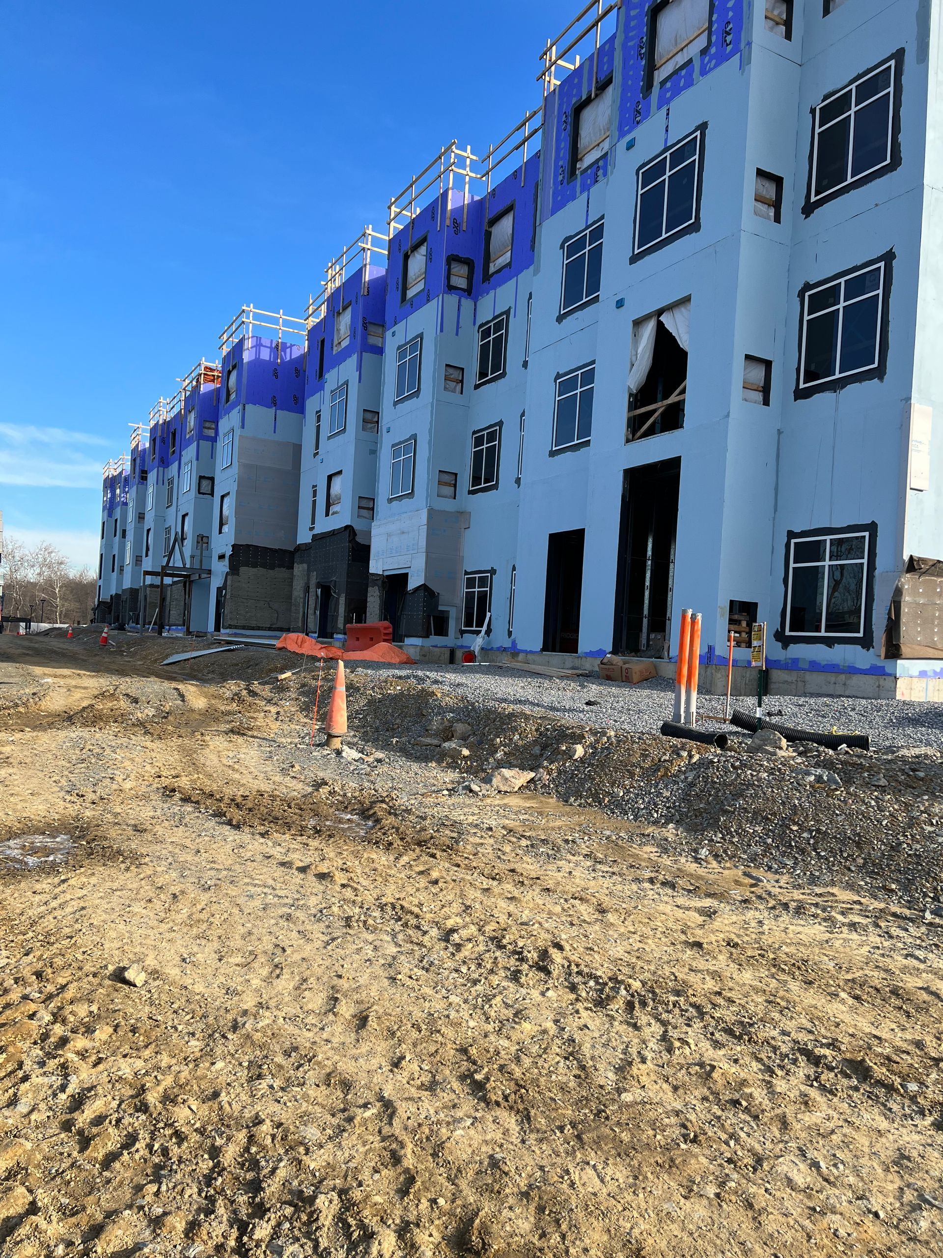 A large white building with purple trim is under construction.