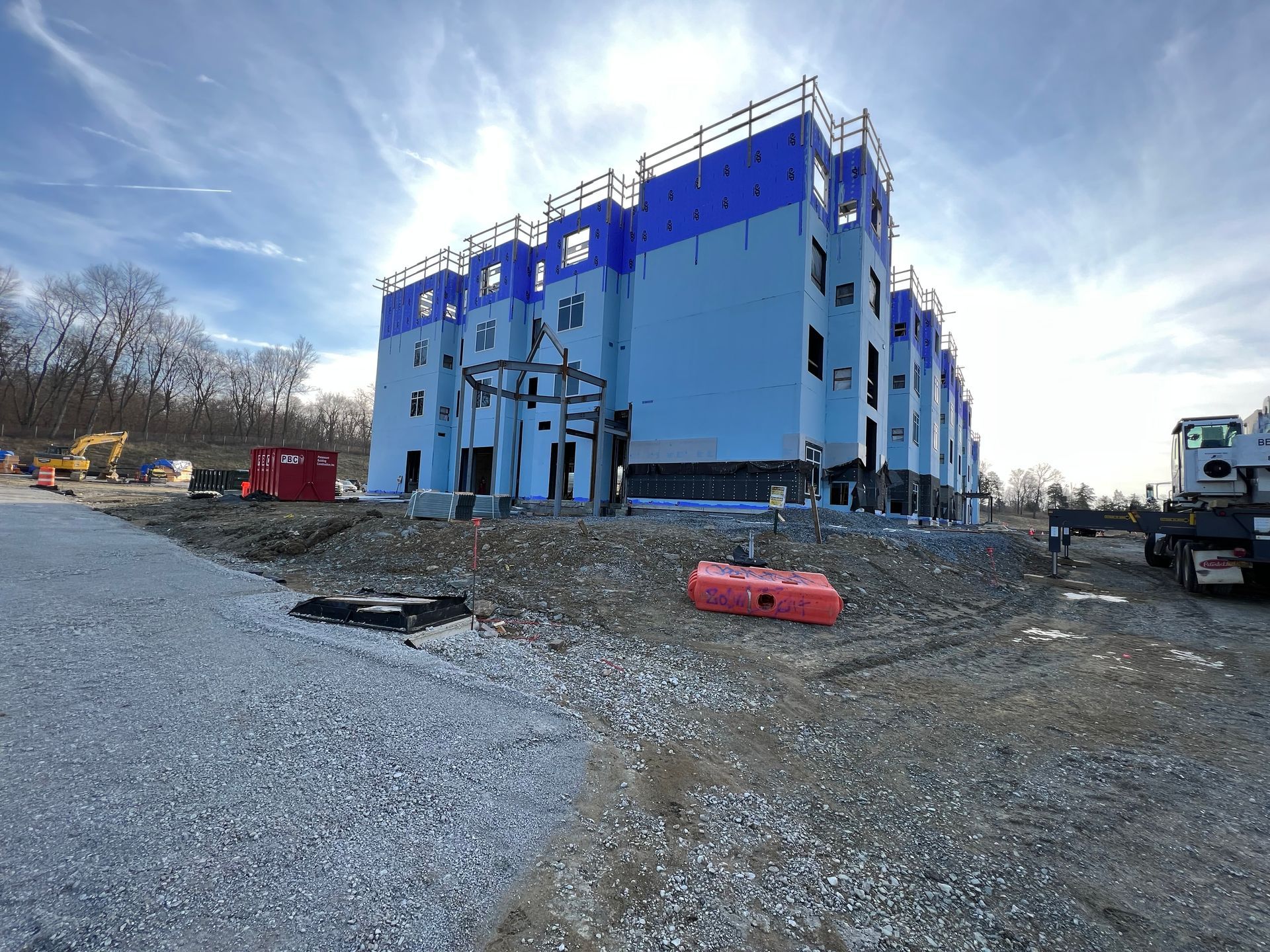 A large blue and white building is being built in a dirt field.