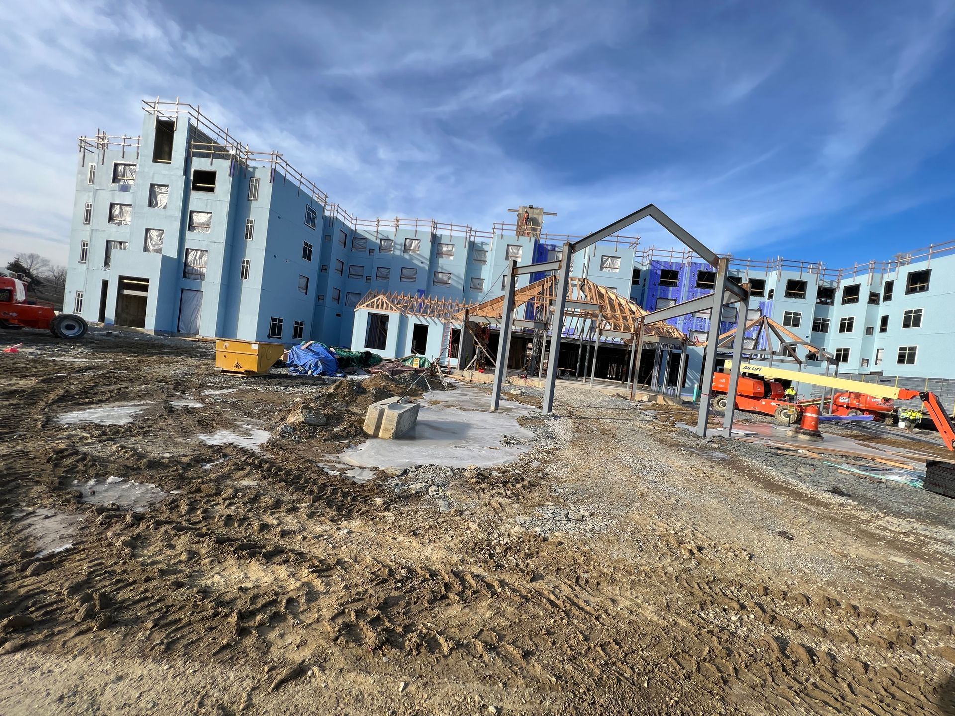 A large building is being built in the middle of a dirt field.