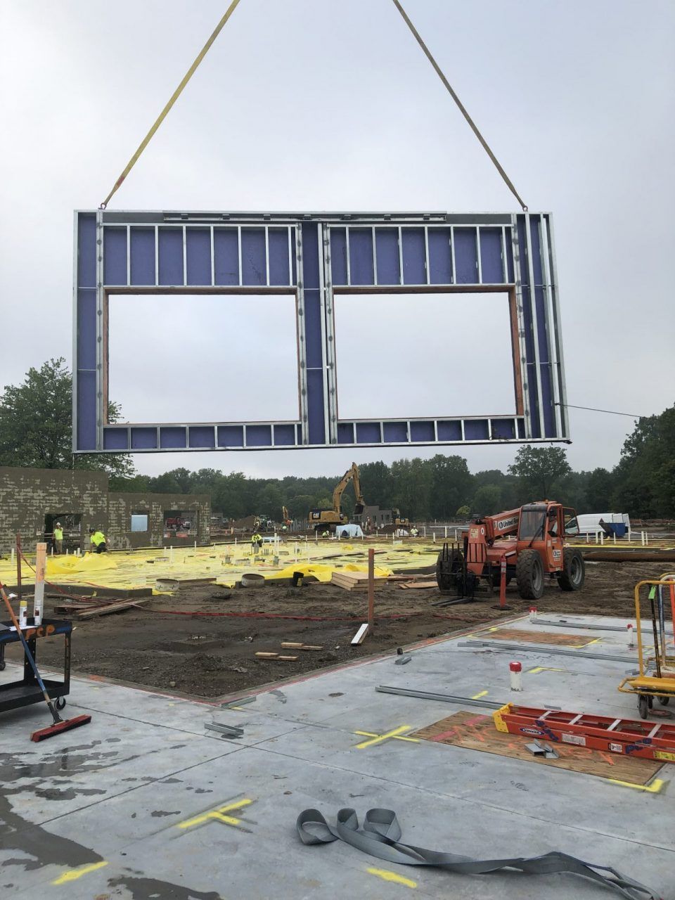 A construction site with a crane lifting a blue frame.