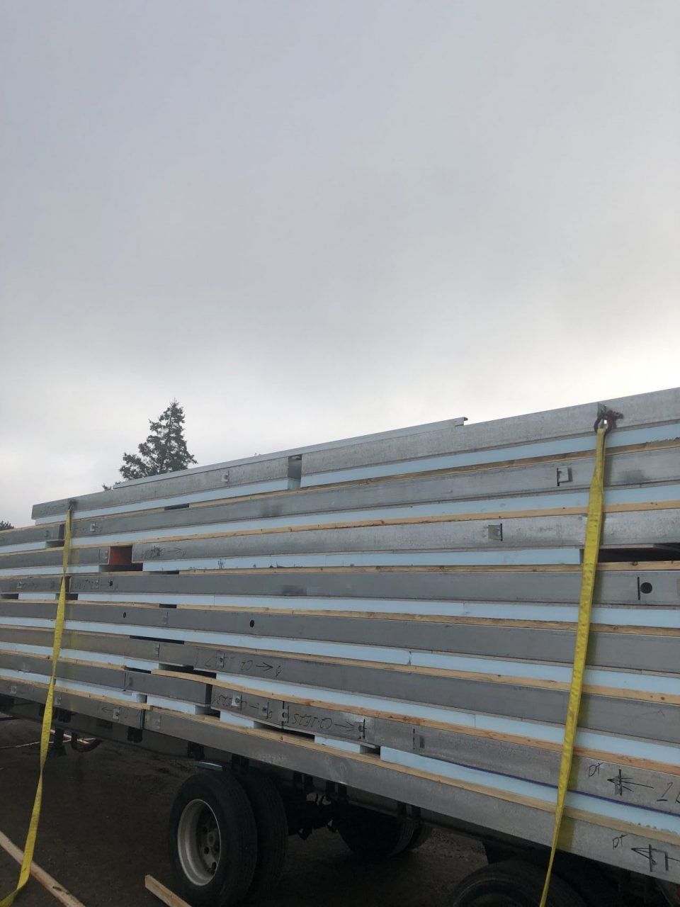 A truck is carrying a large stack of wooden beams.