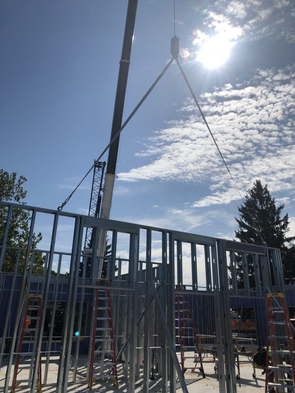 A crane is lifting a metal frame on a construction site.
