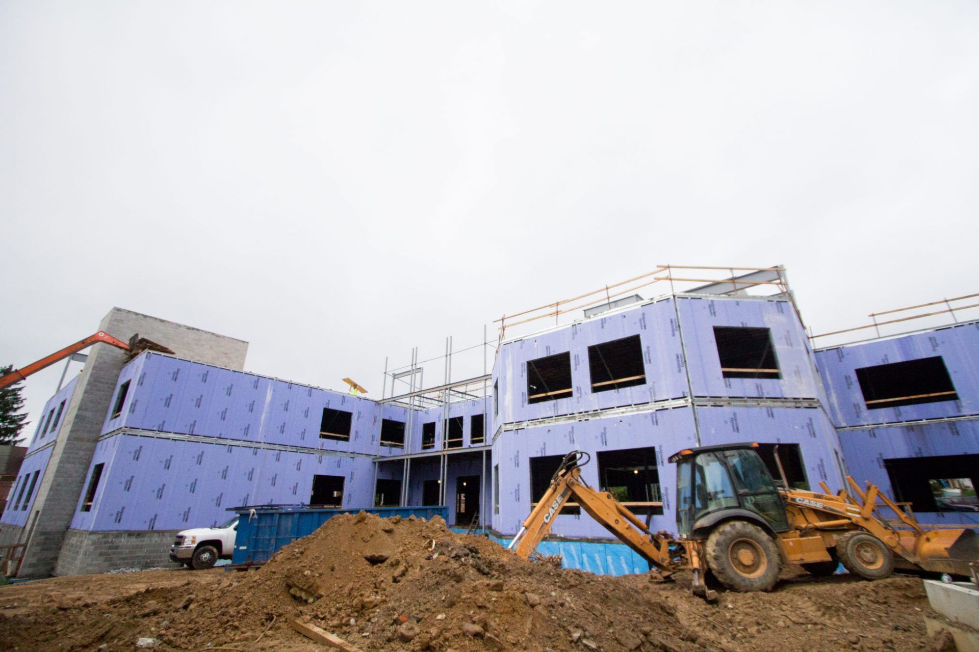A large building is being built with a bulldozer in front of it.