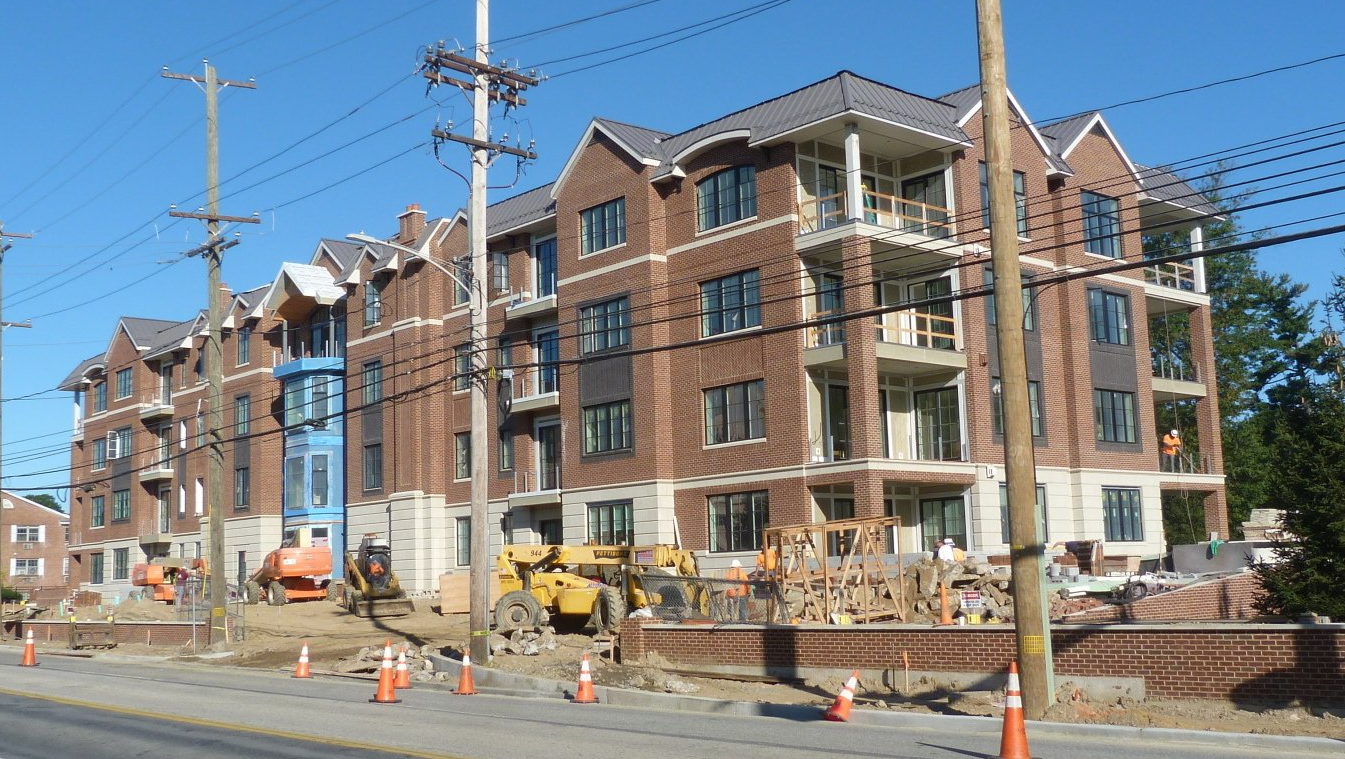 A large brick building is being built on the side of the road.