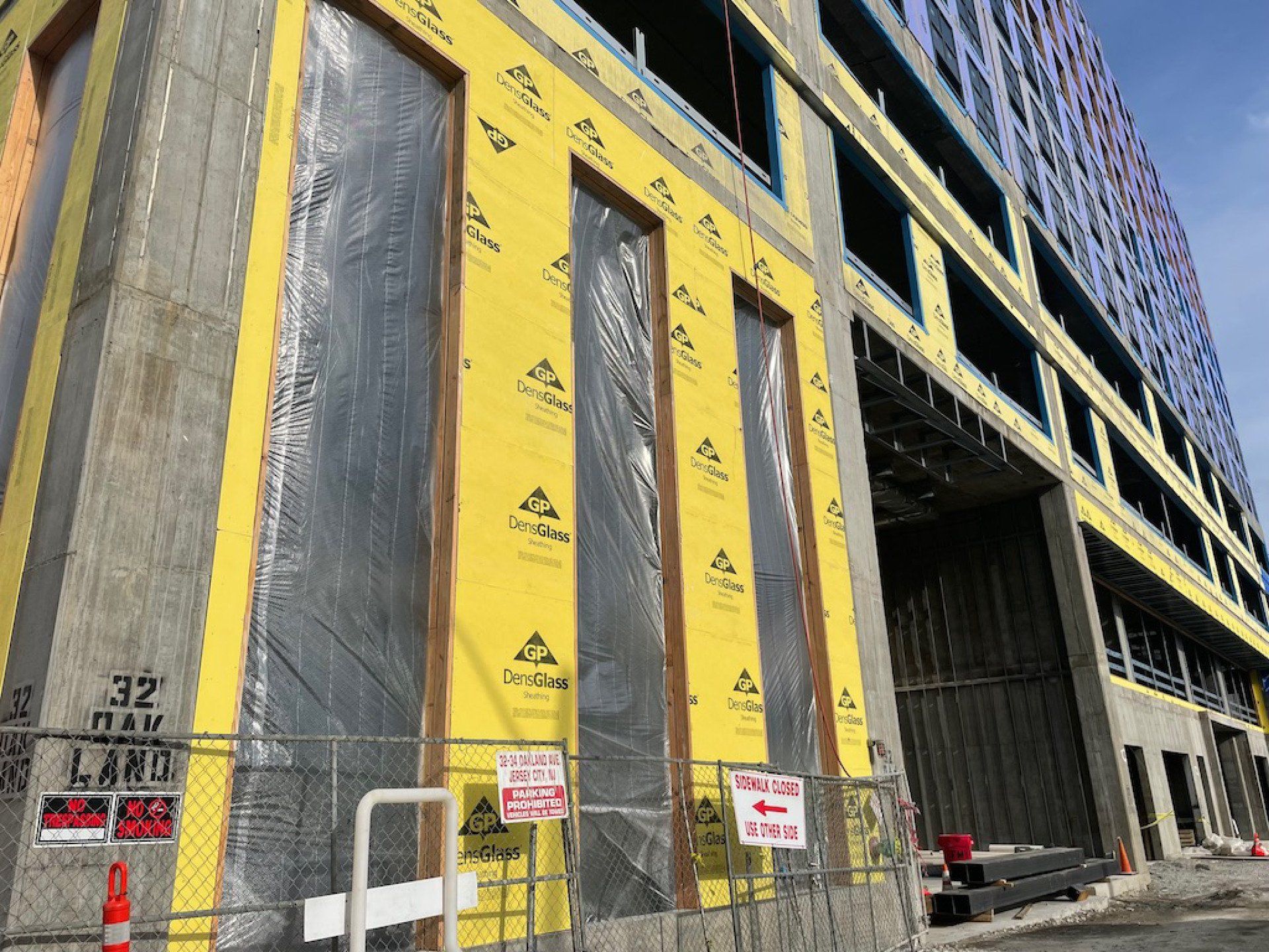 A large building under construction with a lot of windows and a fence around it.