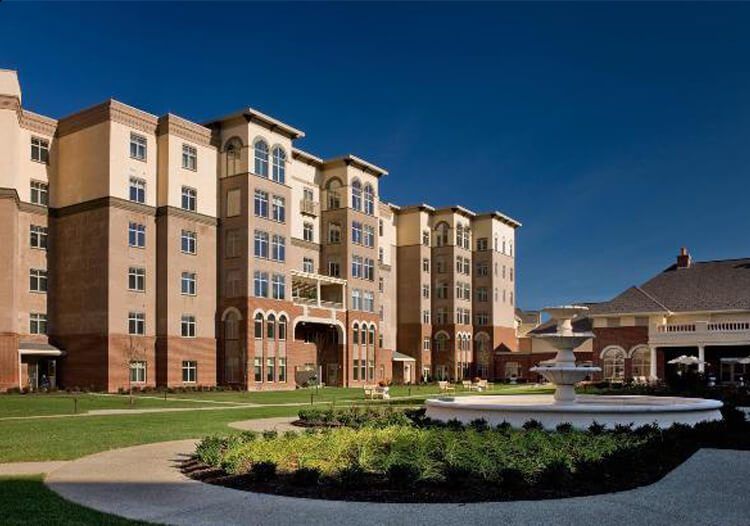 A large apartment building with a fountain in front of it.