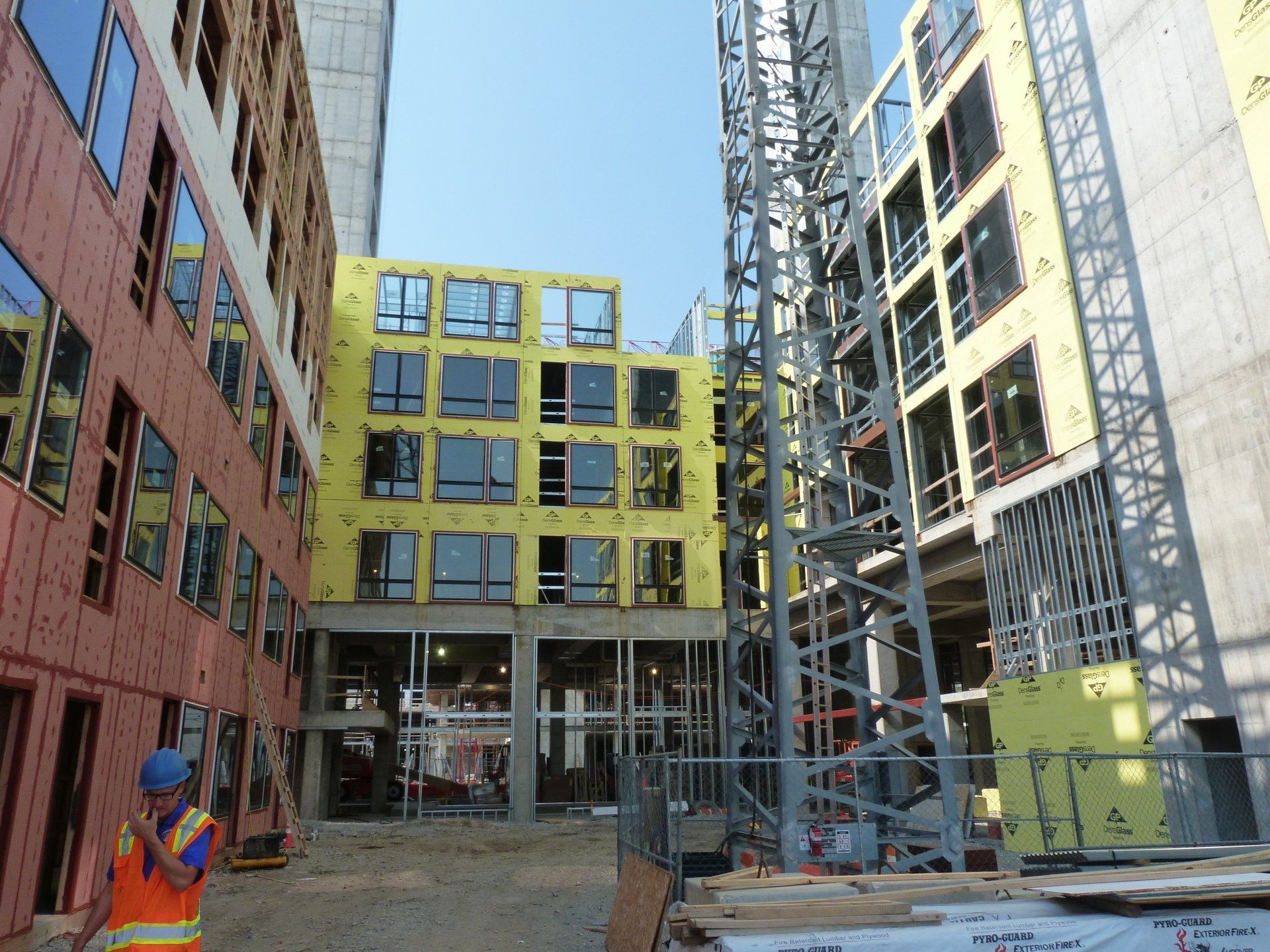 A construction worker stands in front of a building under construction.
