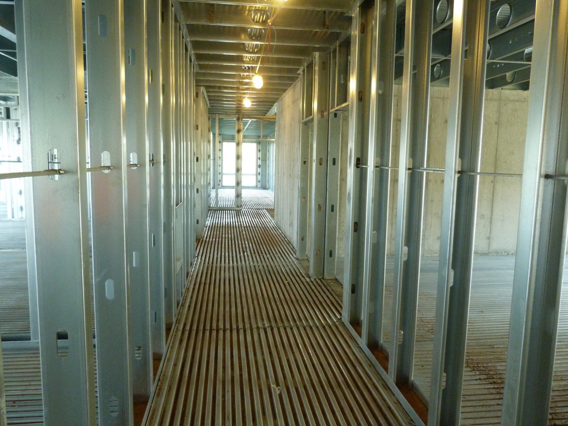 A long hallway with metal frames and a wooden floor.