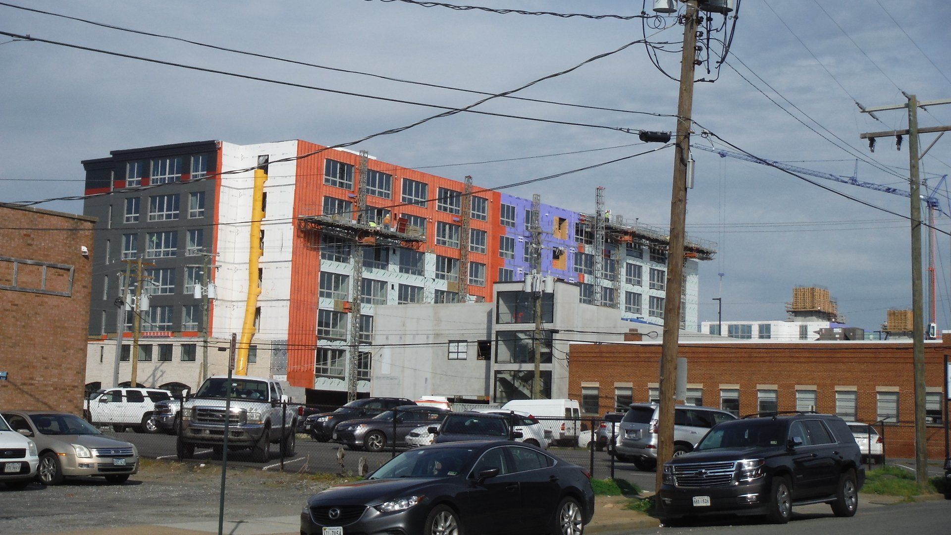 Cars are parked in front of a building under construction.
