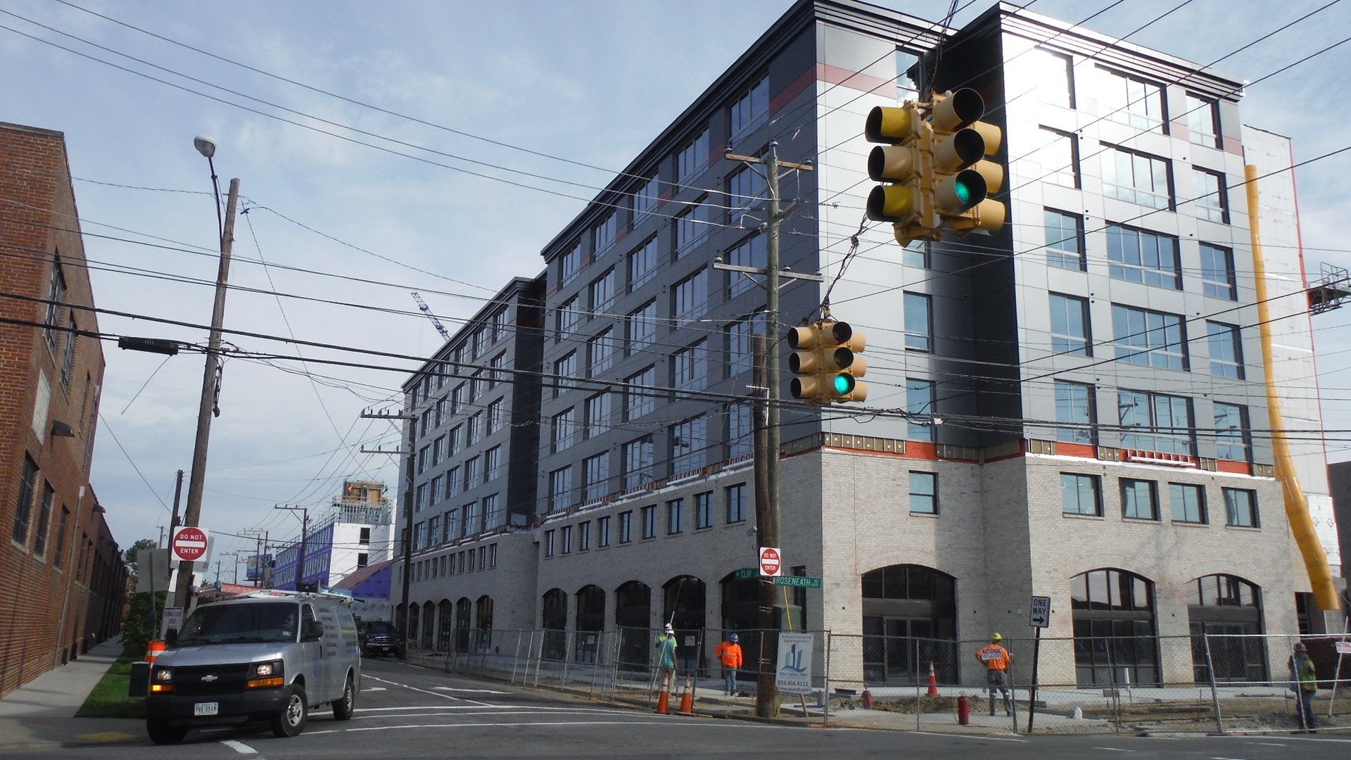 A van is driving past a large building under construction.