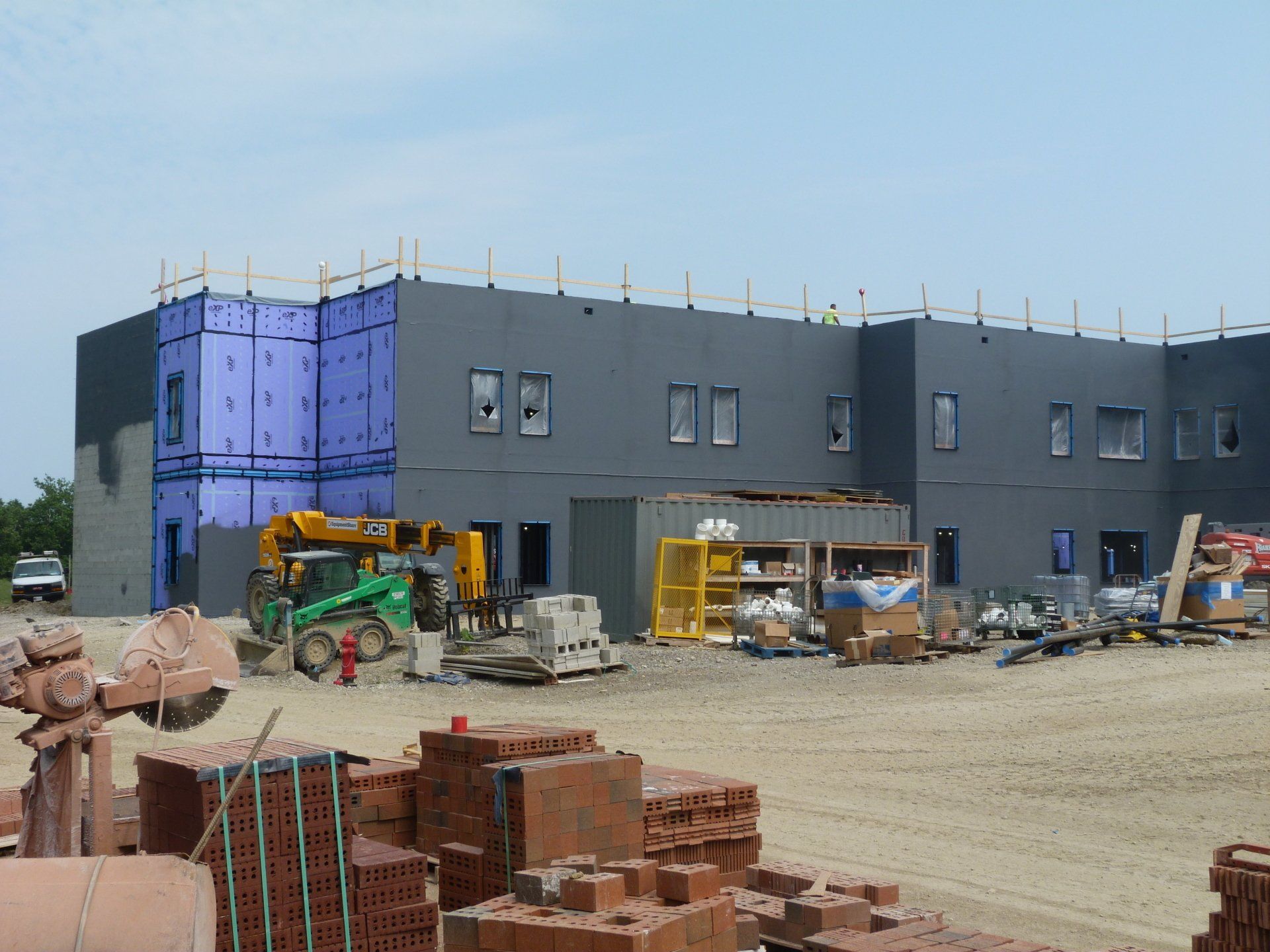A large building under construction with a lot of bricks in front of it.