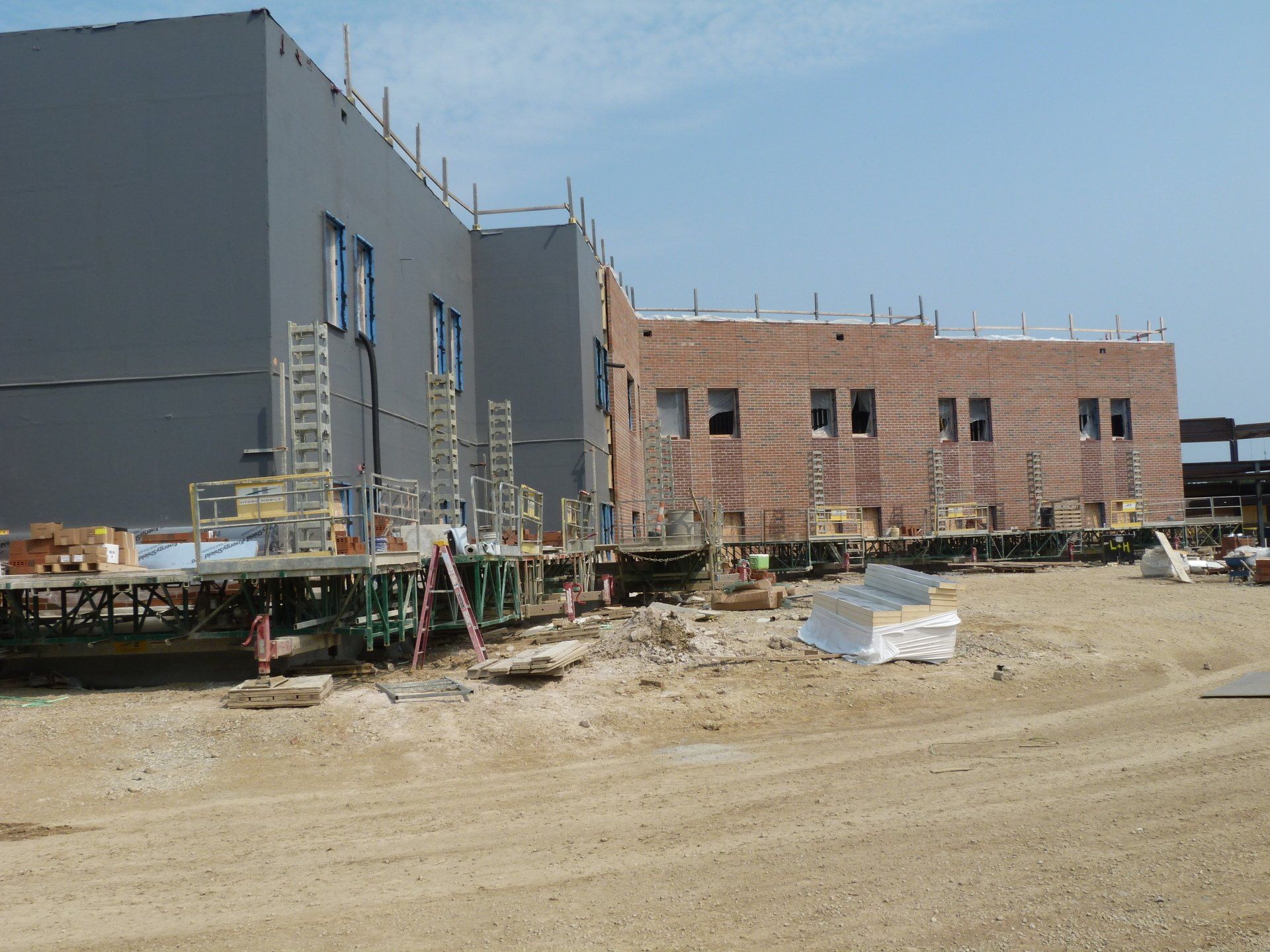 A construction site with a large brick building in the background.