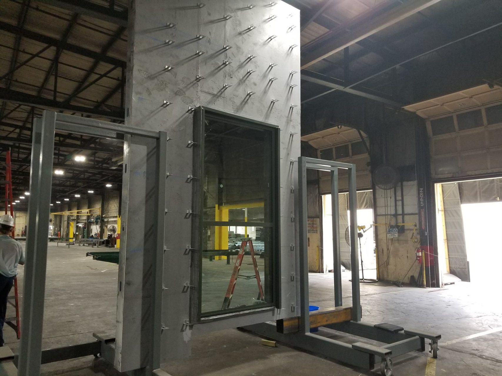 A man is standing next to a ladder in a warehouse.