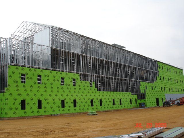 A large building is being built with green insulation.