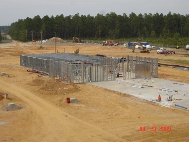A large building is being built in a dirt field.