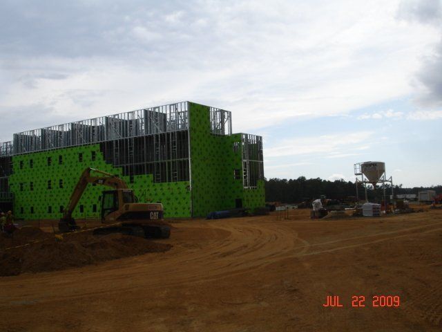 A large building is being built in the middle of a dirt field.