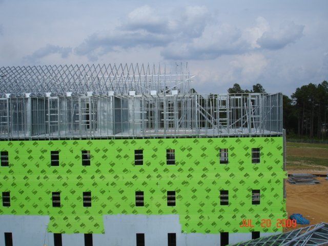 A building under construction with green insulation on the side.