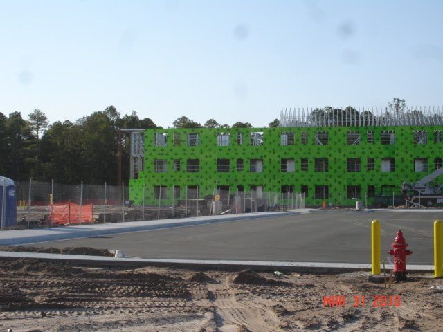 A large green building under construction with a fire hydrant in front of it.