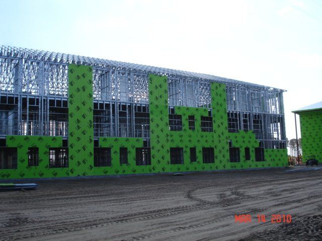 A large building is being built with green insulation.