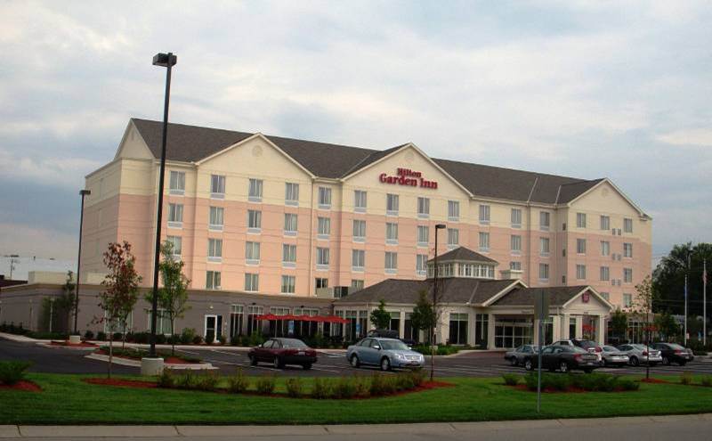 A large hotel with cars parked in front of it.