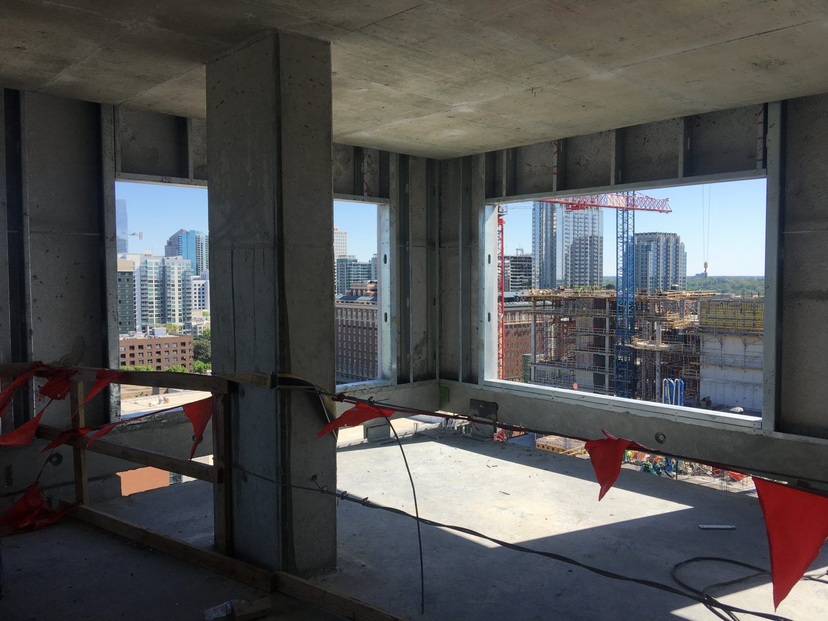 A building under construction in a city with a lot of windows and red flags.