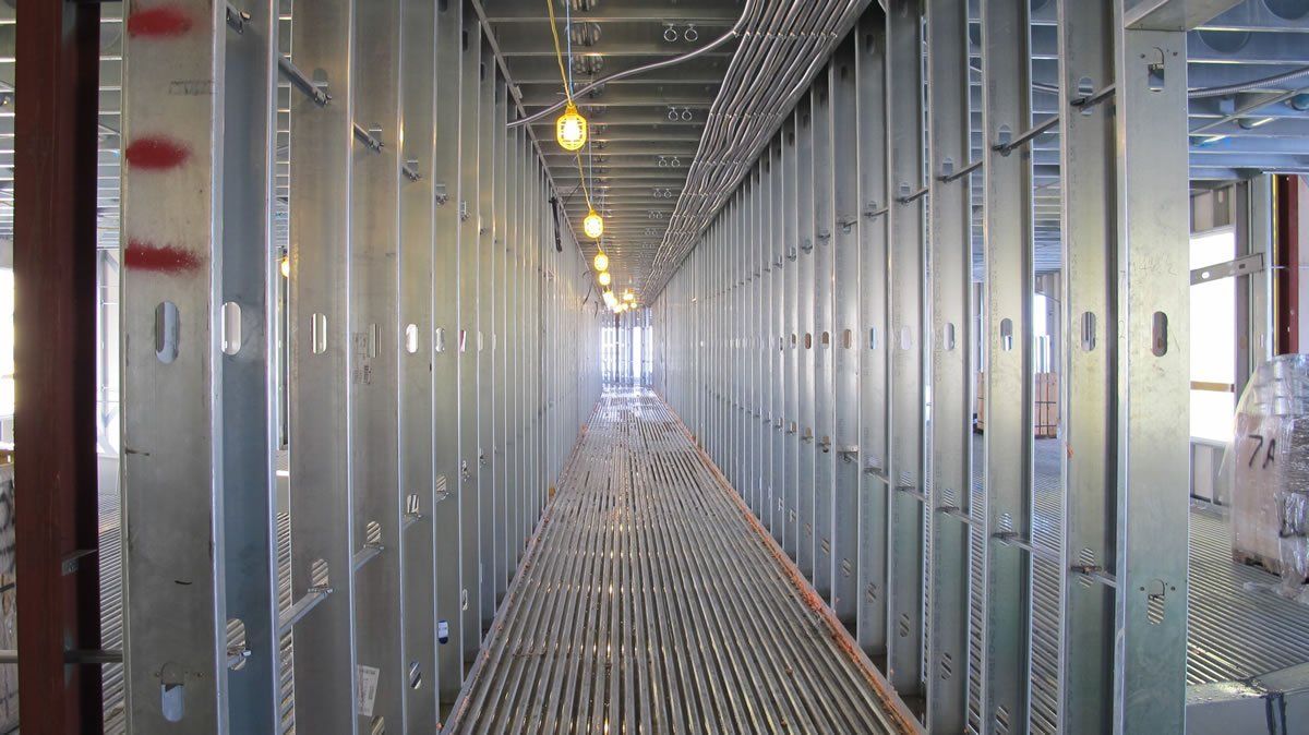 A long hallway in a building under construction with a lot of metal walls.