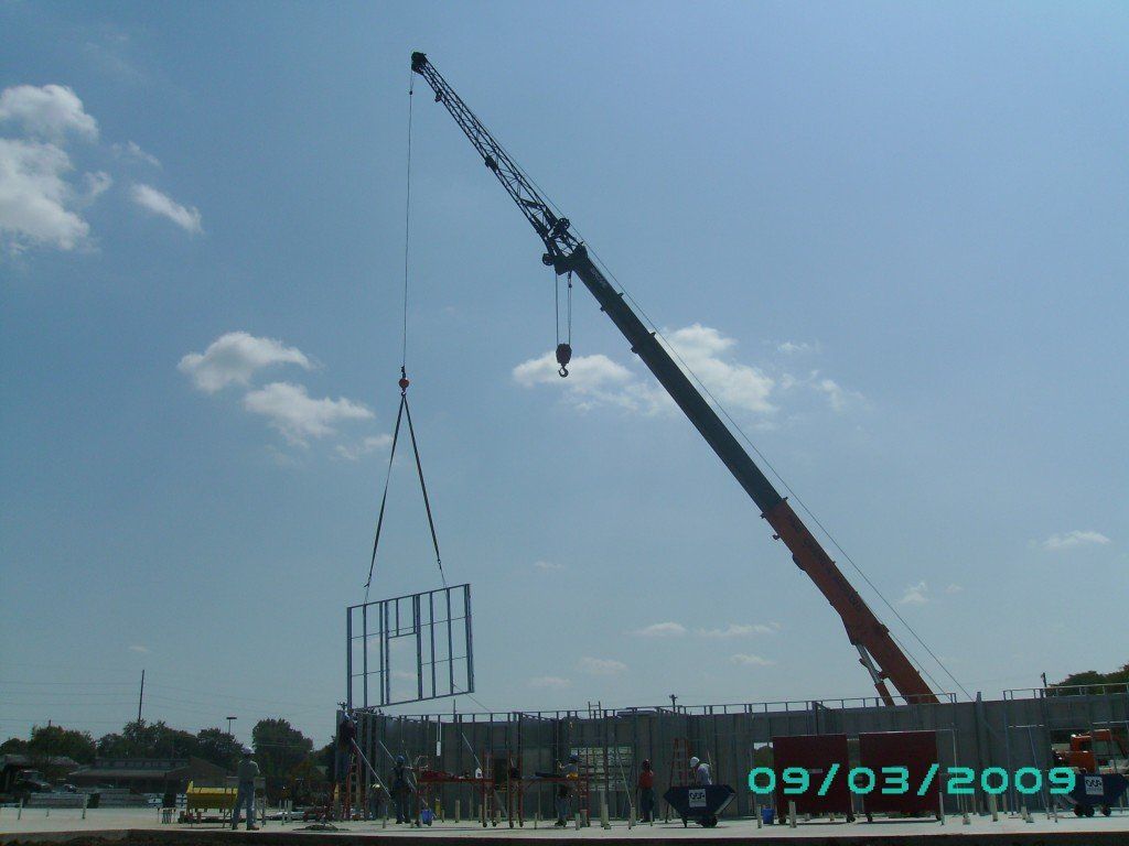 A large crane is lifting a large piece of metal in the air.