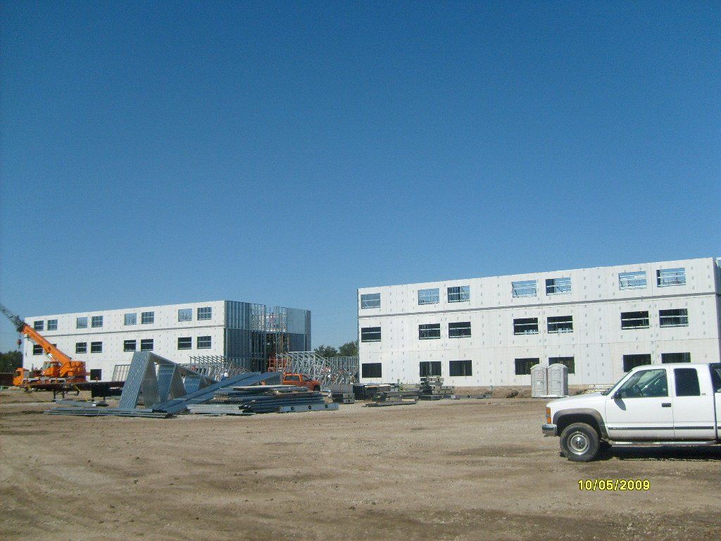 A white truck is parked in front of a building under construction.