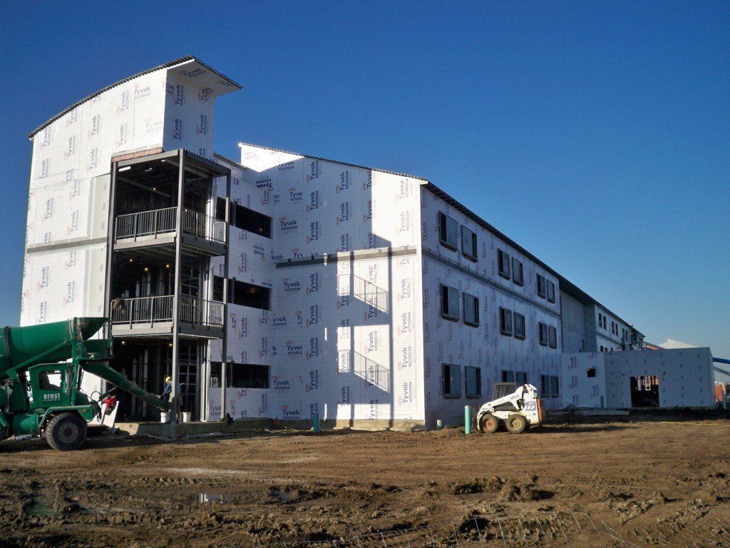 A large building under construction with a concrete mixer in front of it.