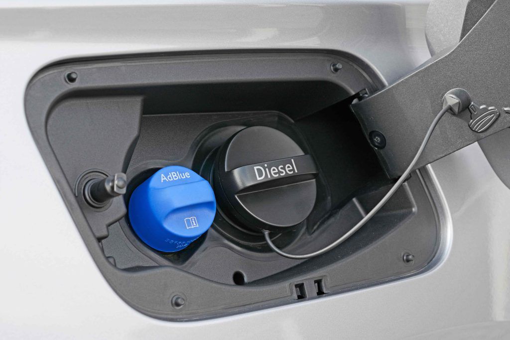 A close up of a diesel fuel cap and adblue cap in a car.