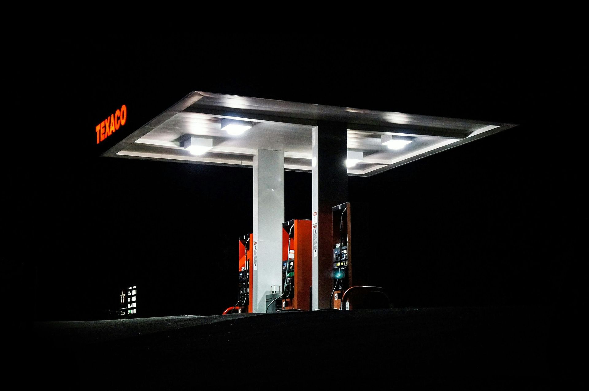 A texaco gas station is lit up at night.