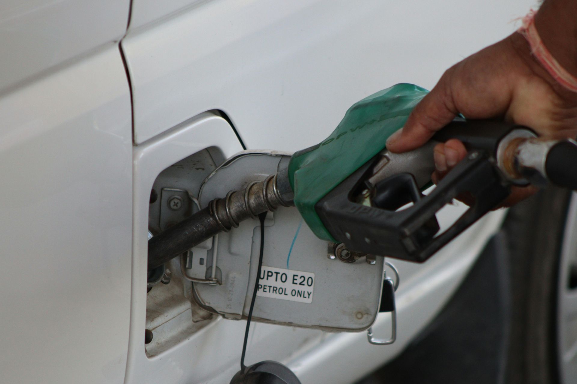 A person is pumping gas into a white car.