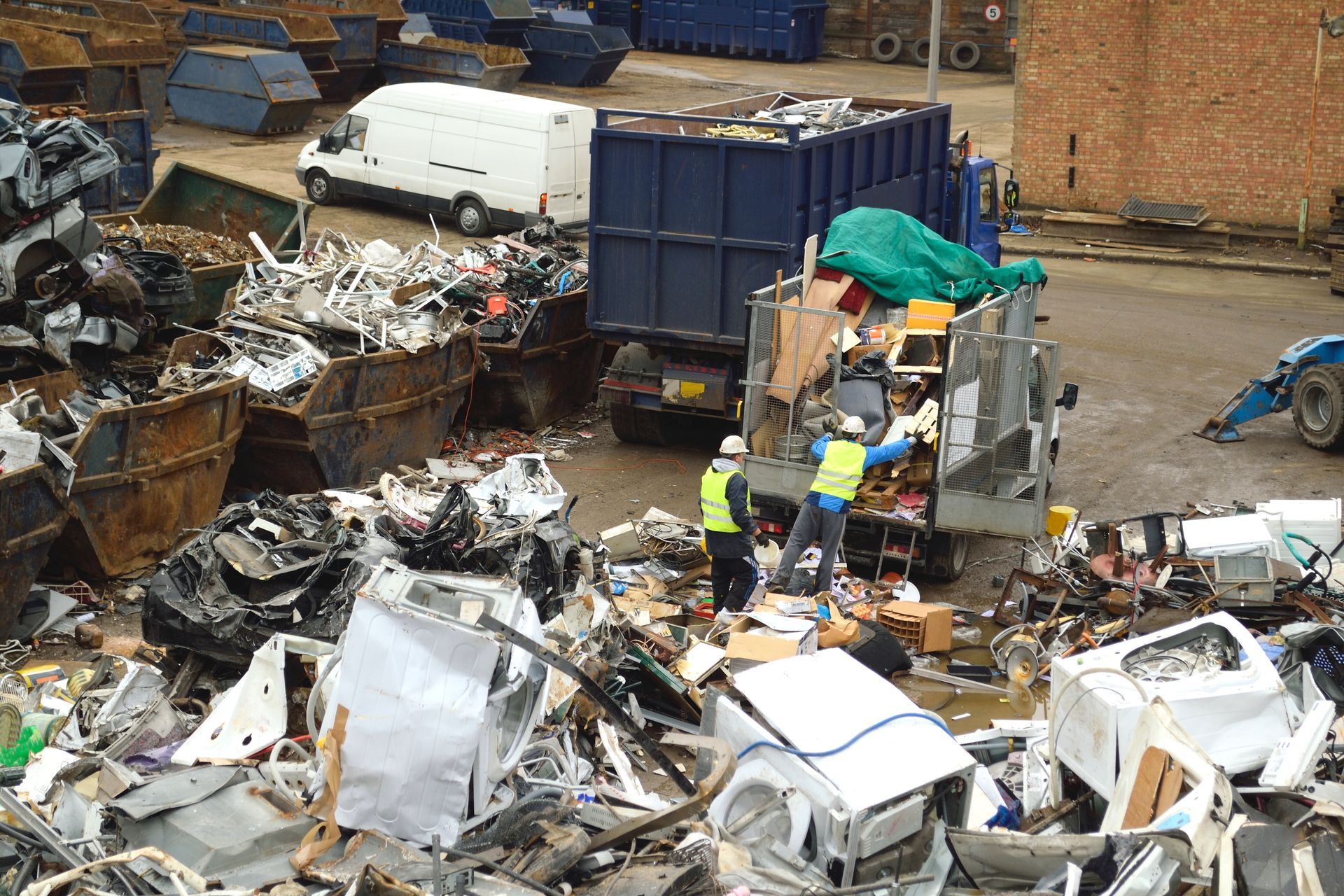 Workers in safety gear loading debris onto a truck for efficient scrap recycling services.