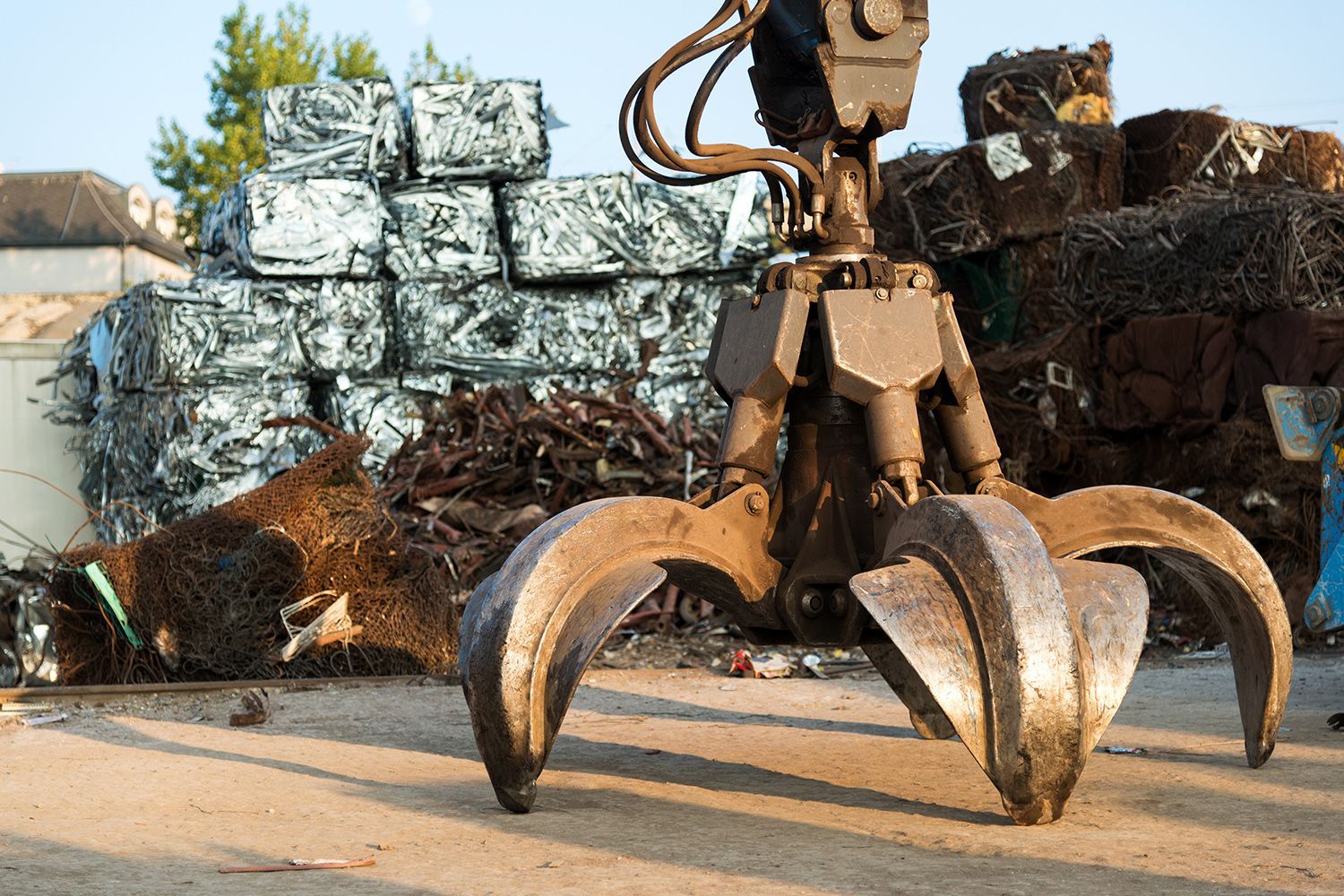 A large tracked excavator moving a steel pile at a busy metal recycling yard. A large tracked excavator moving a steel pile at a busy metal recycling yard.