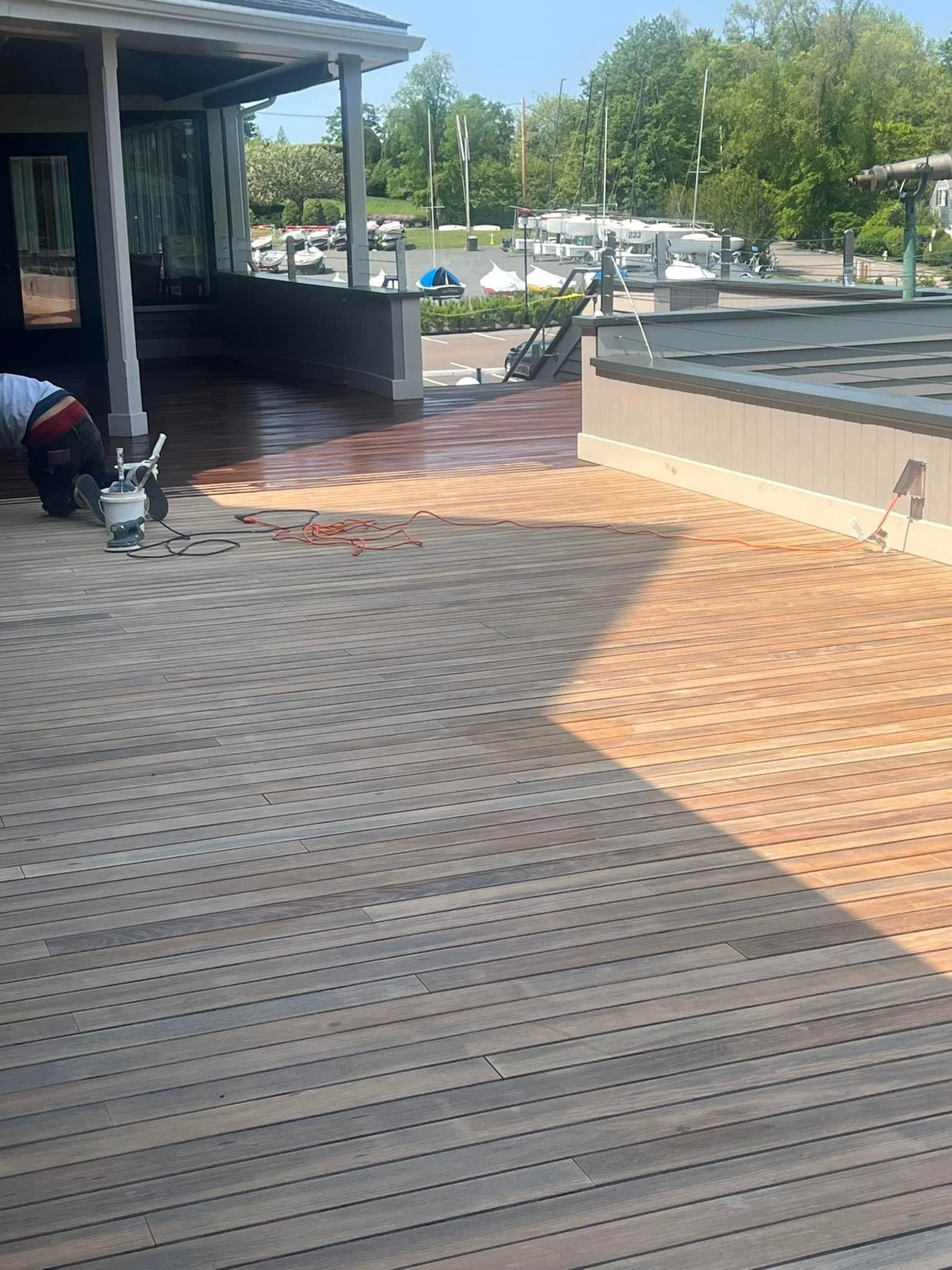 A man is kneeling on a wooden deck in front of a building.