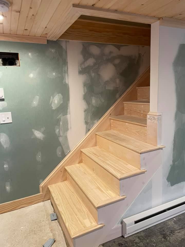 A wooden staircase is being built in a basement.