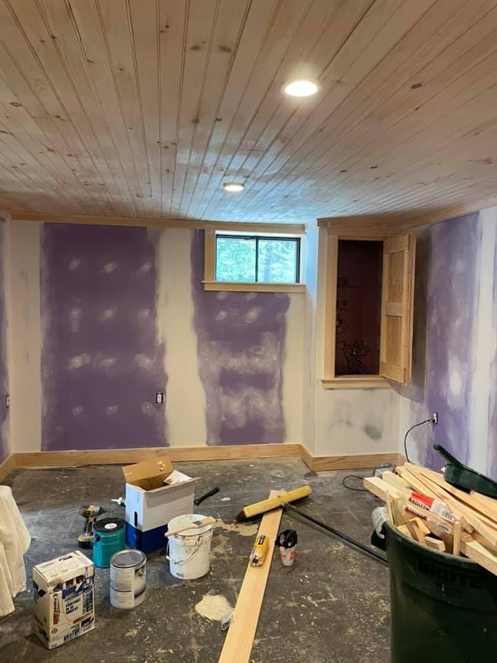 A room with purple walls and a window is being painted.