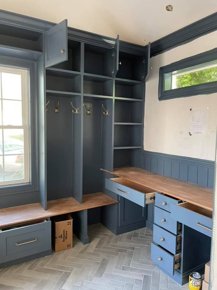 A room with a desk , shelves , drawers and a window.