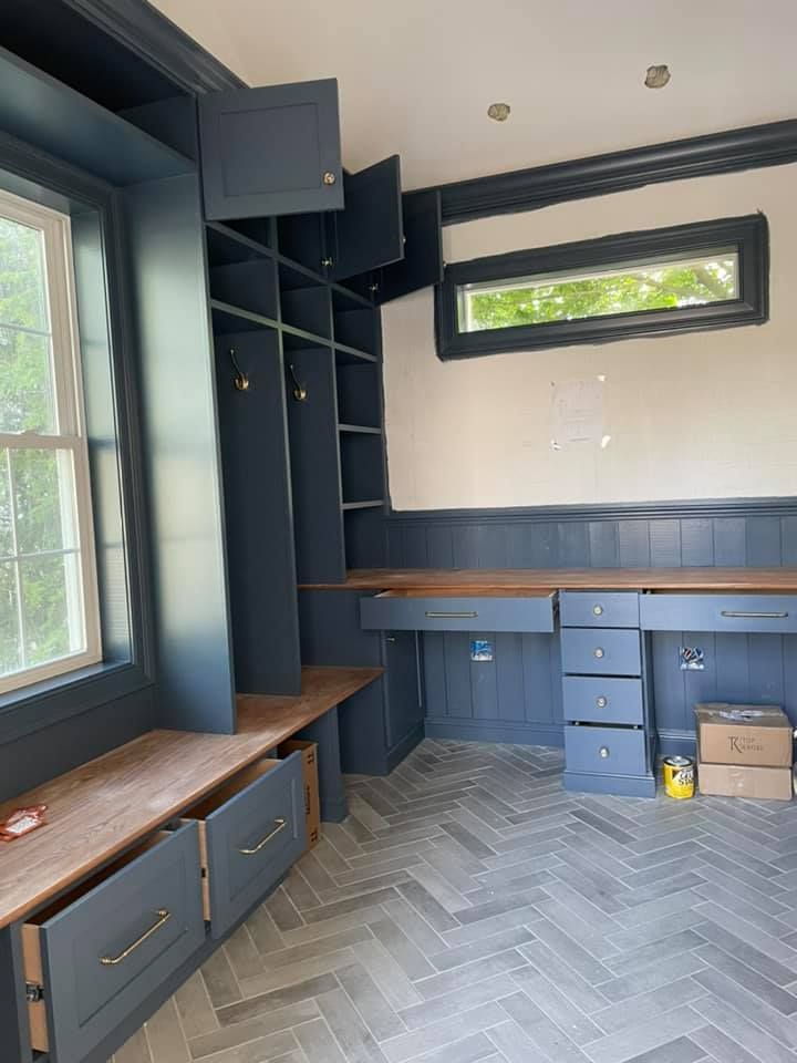 A room with a desk , drawers , shelves and a window.