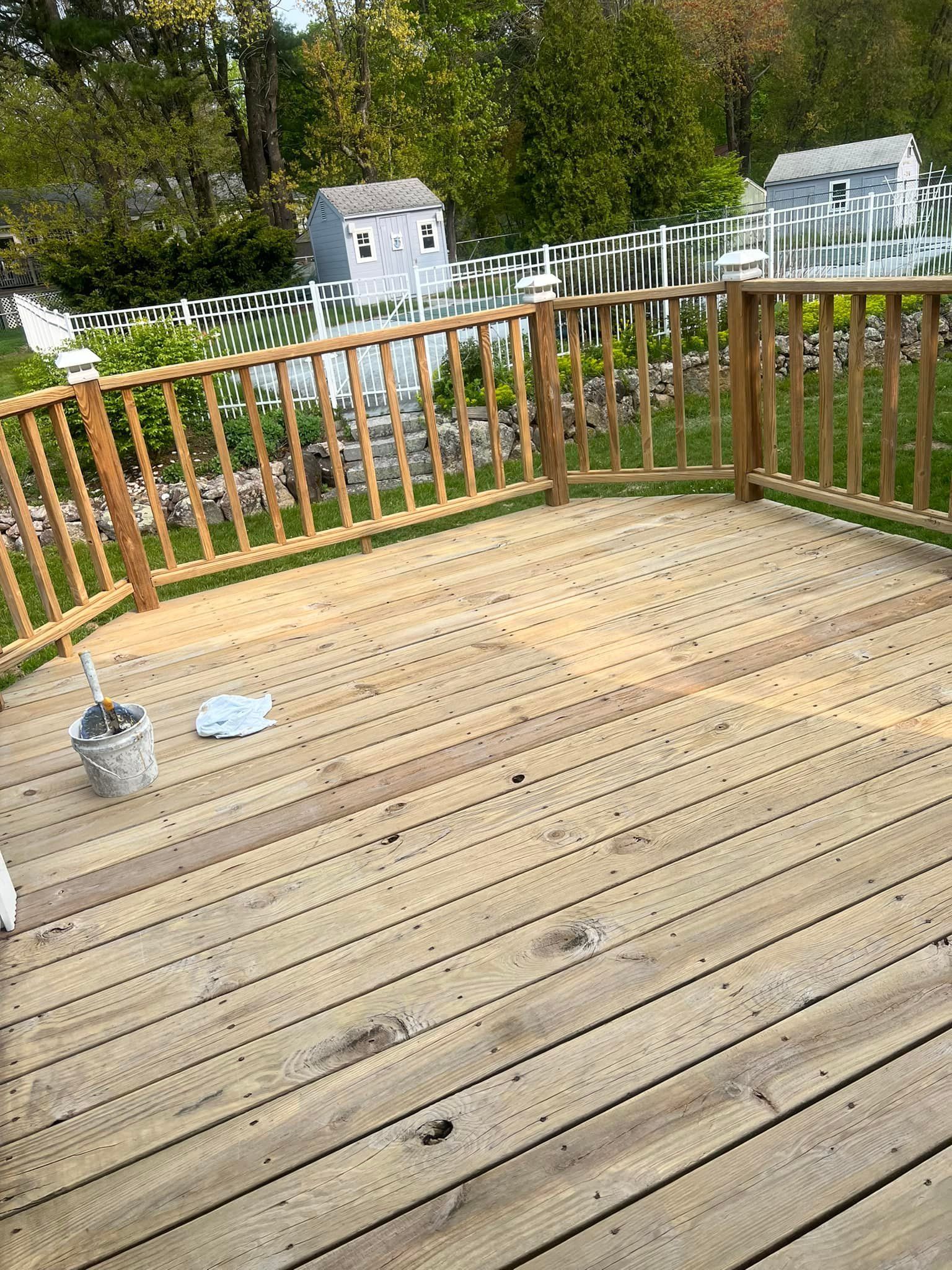 A wooden deck with a fence and a bucket of paint on it.