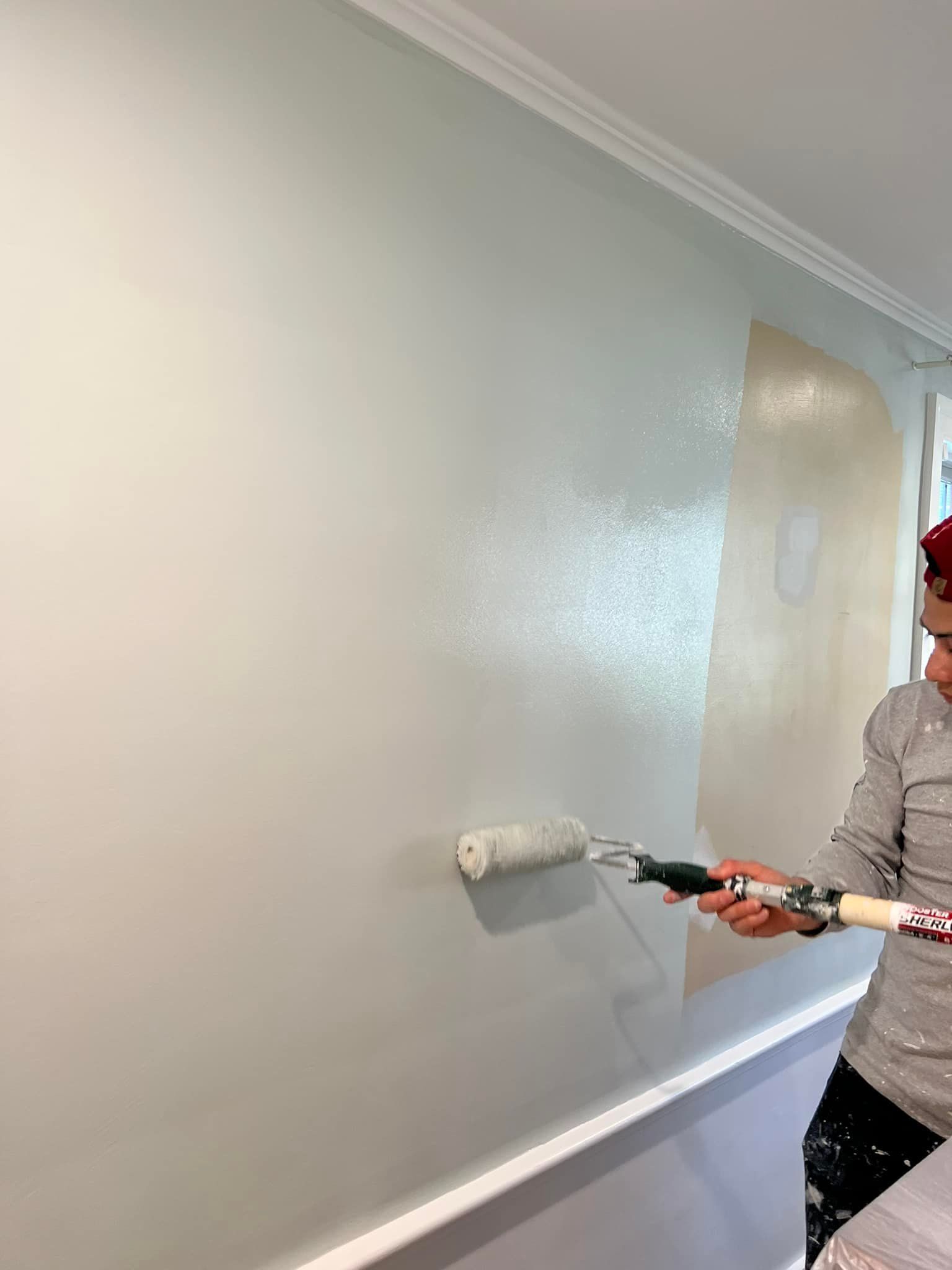 A man is painting a wall with a paint roller.