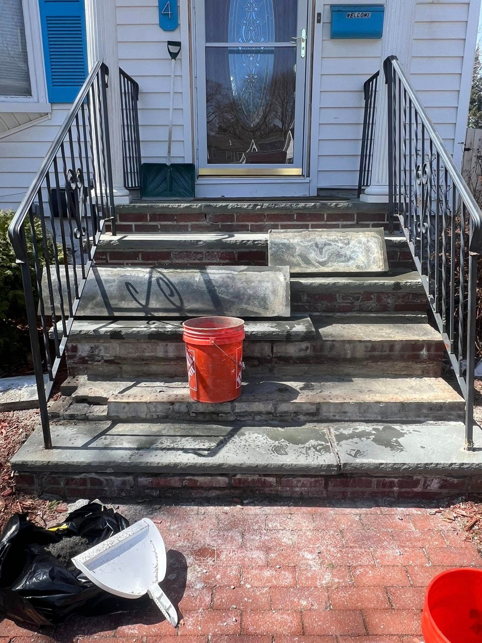 A red bucket is sitting on the steps of a house.